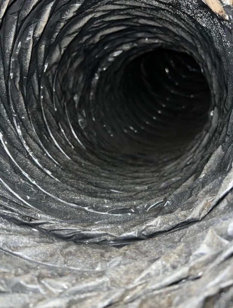 Dust-lined flexible AC duct interior before cleaning