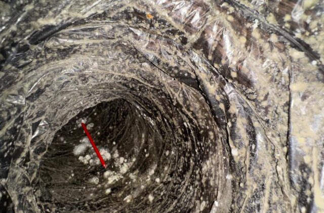 Heavy debris and buildup inside an AC duct before cleaning
