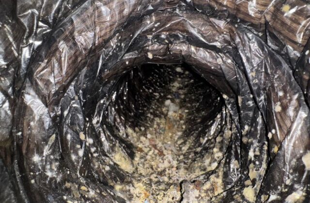 Debris collected at the bottom of an AC duct before cleaning